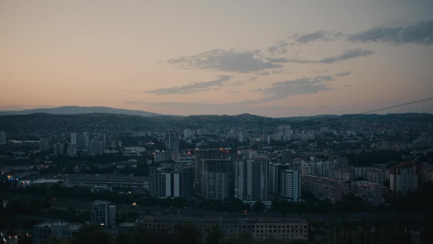 A view of a metropolis with tall buildings and in the background a range of mountains during sunrise