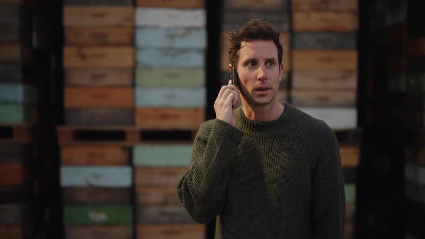 Man talks on phone standing in warehouse