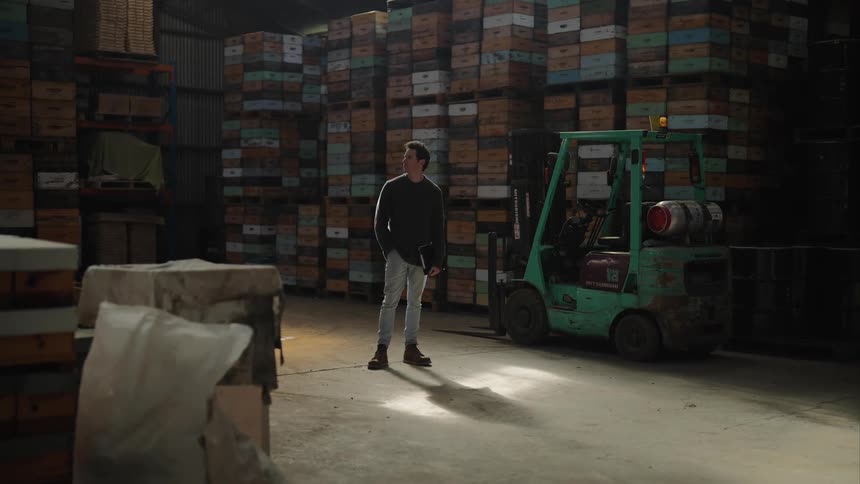 A man stands surrounded by stacked boxes in a large warehouse