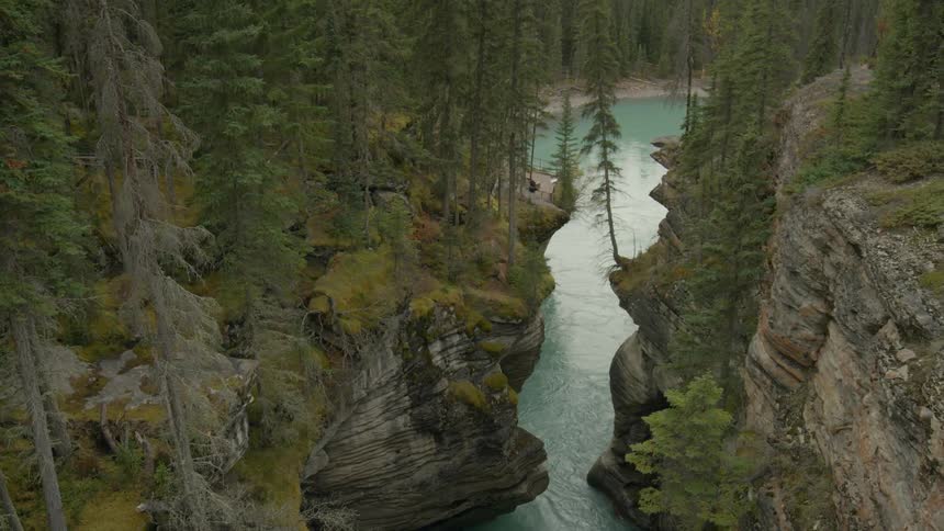 The water below is surrounded by cliffs and tall trees