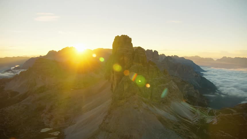 Sun glares from horizon across jagged mountain range