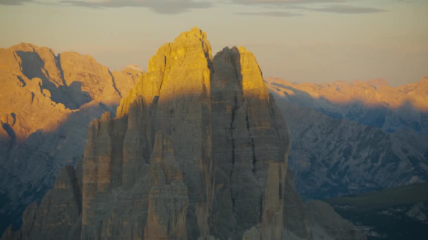 An aerial view of a peak with geological formations surrounded by a natural environment with rocky mountains