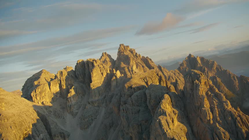 Sunlight highlights portions of jagged mountain on cloudy day