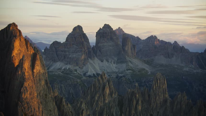 Sand covers base of mountains in badlands at sunset