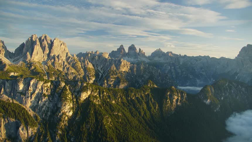 Fog and low lying clouds fill valley between forest covered mountains