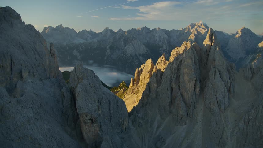 A mountain range with peak formations and cliffs during a sunrise