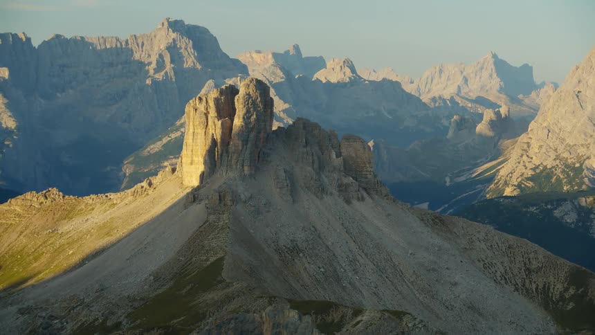 A rock formation on top of a stone hill surrounded by several mountains