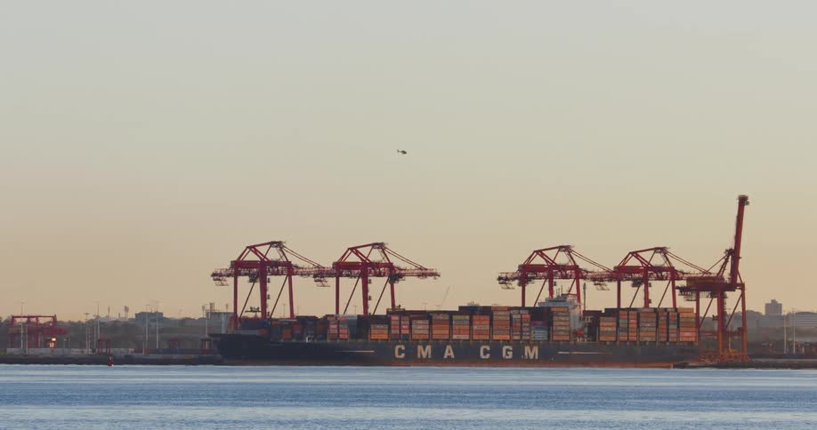 An export ship full of containers near a harbor full of containers