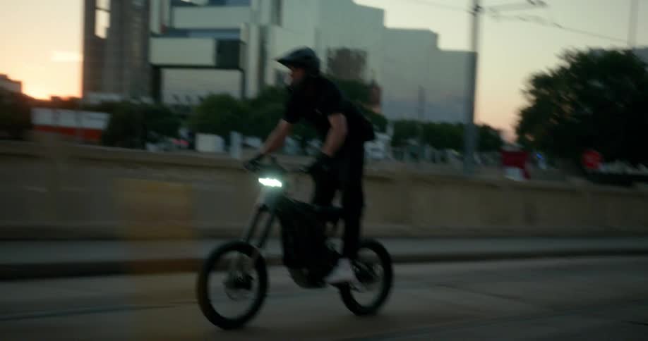 A teenage boy is riding his bicycle on a city street moving out of the way of traffic