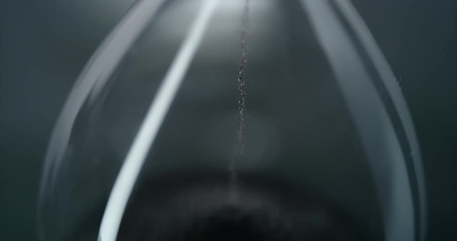 An hourglass where grains of sand are falling downwards