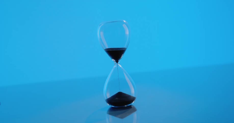 An hourglass where grains of sand are falling into the compartment below