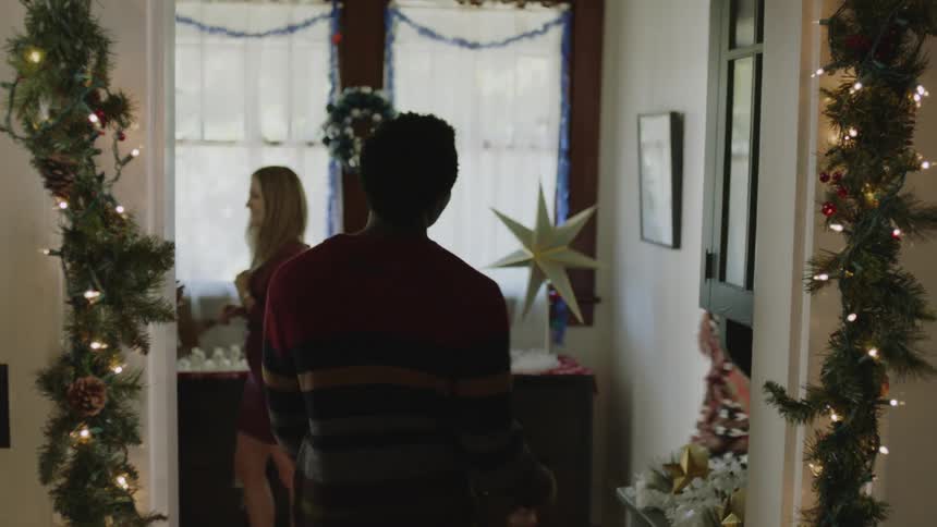 First we see leather shoes walking down stairs then the camera rises to show the young man as he pirouettes into a room decorated for xmas and smiles at the 4 other people there as one hands him a wrapped gift as he walks into another room