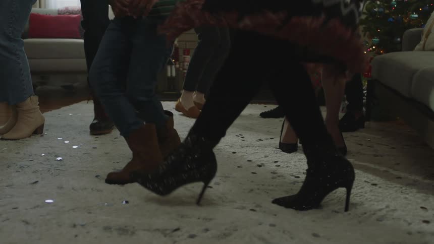A group of people are dancing together in the living room at christmas time