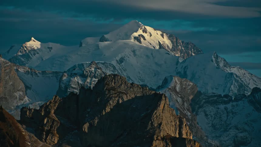 Aerial of rocky mountain with snow on peak during sunrise