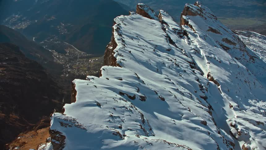 Aerial view of snow on the slopes of a mountain range at daytime