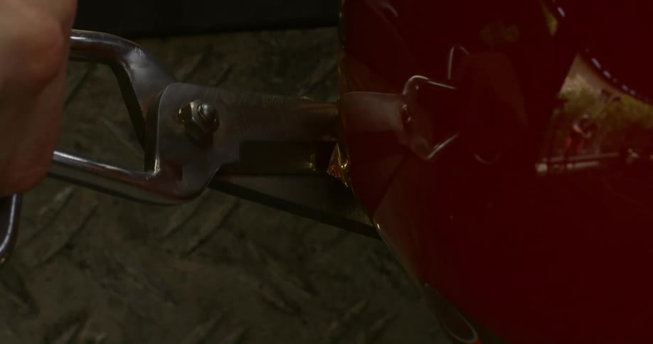 A large scissors cutting red gelatinous material