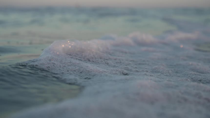 A closeup of small ocean waves in motion with foam