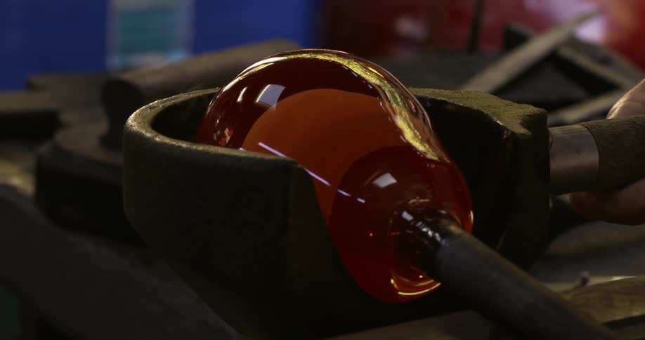 A human hand crafting a circular glass vase