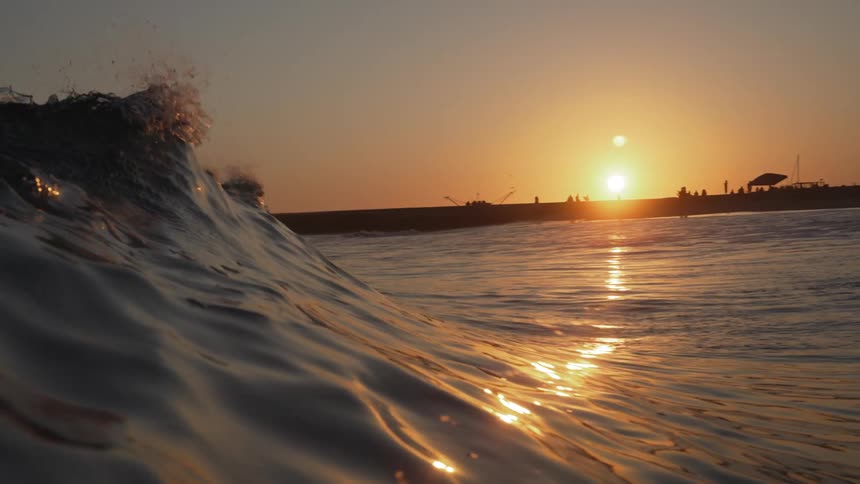 A wave breaking in the sea as the surface is illuminated with sunset sunlight