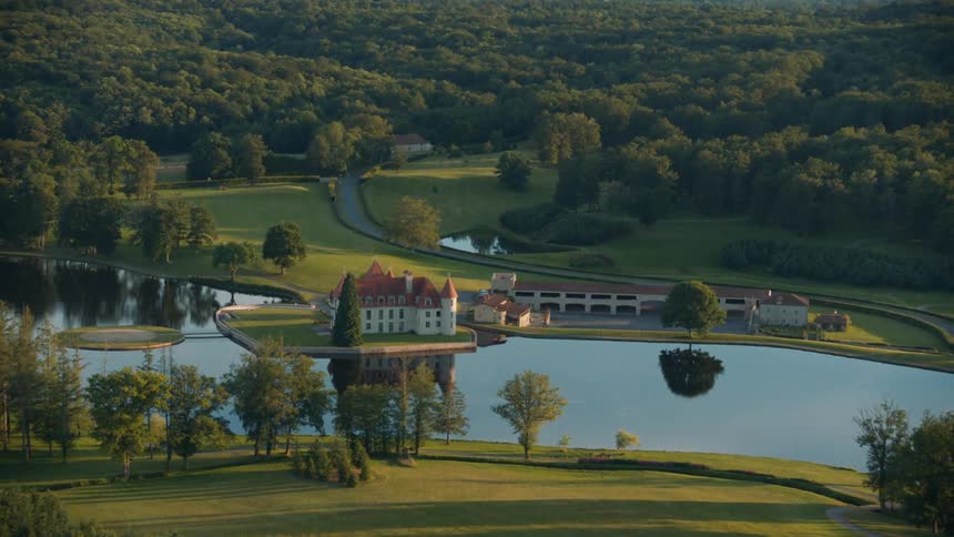 Aerial view of a residence amidst a lake and a natural environment with forests