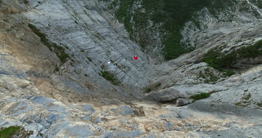 Three people jump off the cliff with their wingsuits