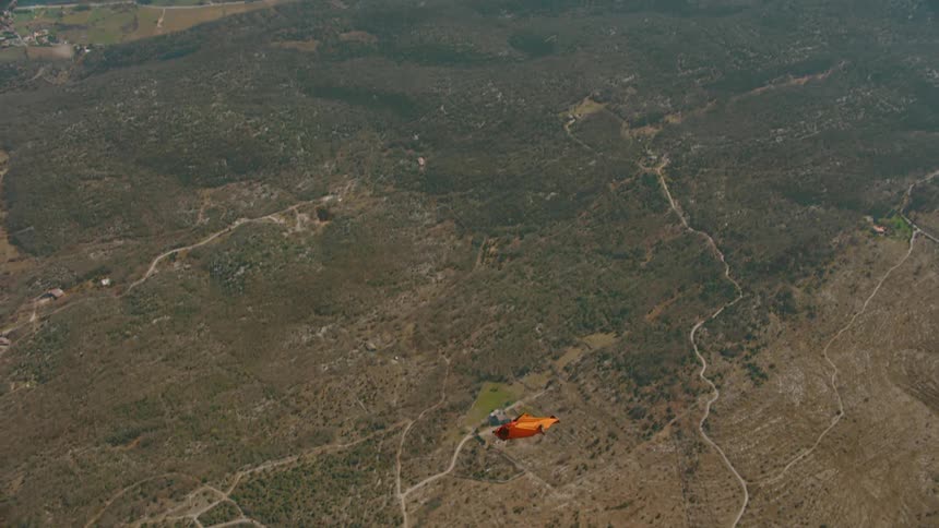 Two people wearing wingsuits flyover landscape