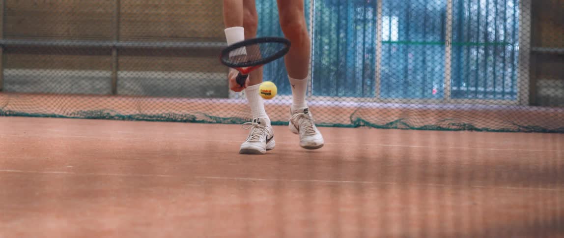 A man hits a ball with a tennis racket and lifts it up