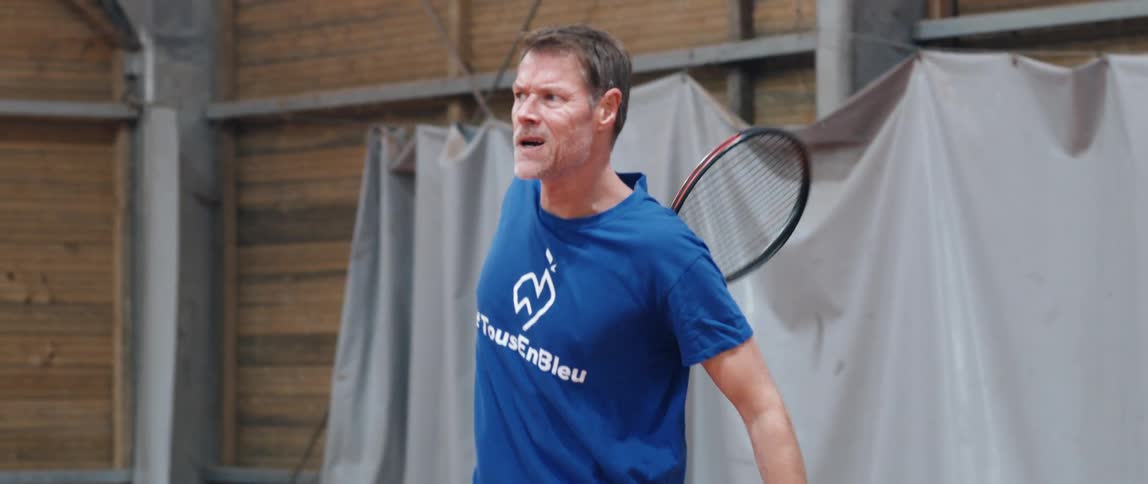 An adult man is hitting a ball with a tennis racket