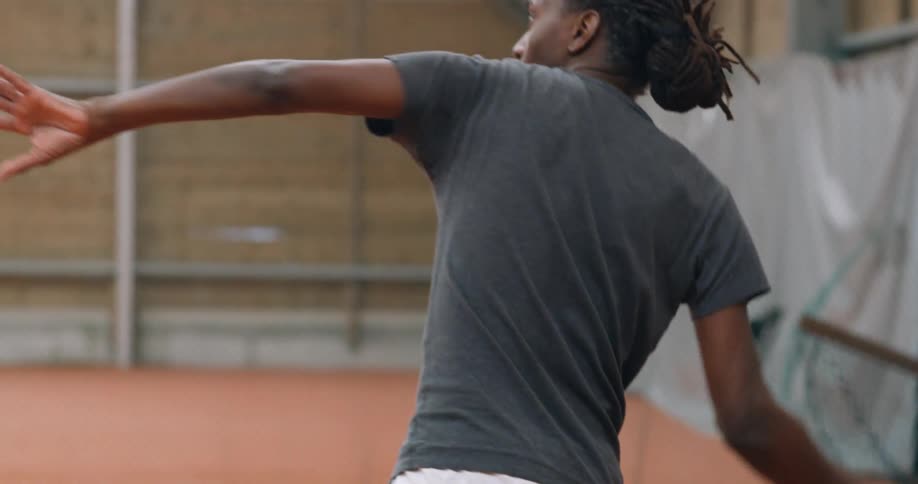 A man swings a racquet and hits a tennis ball on a clay court