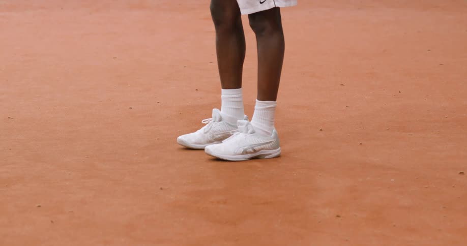 A person wearing a sneakers and a socks in a tennis court