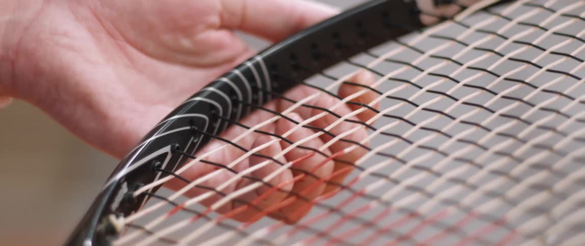 A person holding a tennis racket and spinning it with their hands