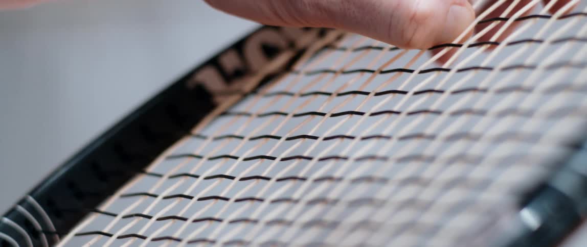 A person holding a tennis racket and spinning it with their hands