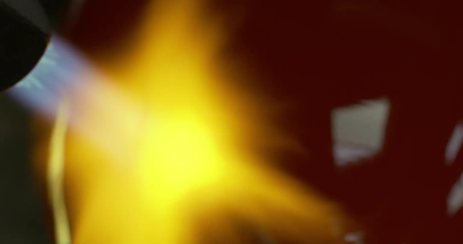 Close up of a torch heating the surface of a piece of glassware