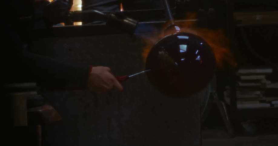 A persons hand placing a metal into a stove burning flames