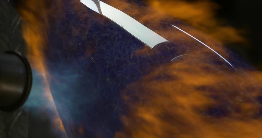View of a torch emitting flames onto a blue crystal vase