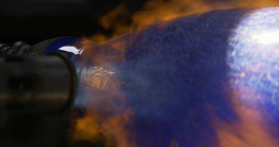 A blowtorch shooting fire into a rotating glass vase