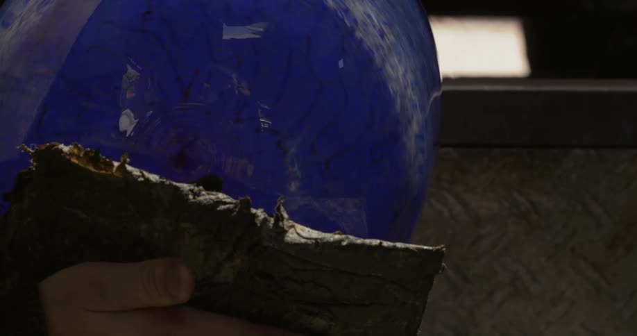 A person is shaping a blue vase that is rotating