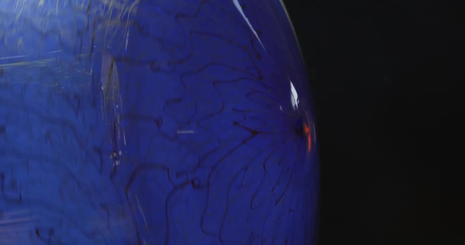 Closeup of a spinning blue crystal vase in the final stages of manufacturing