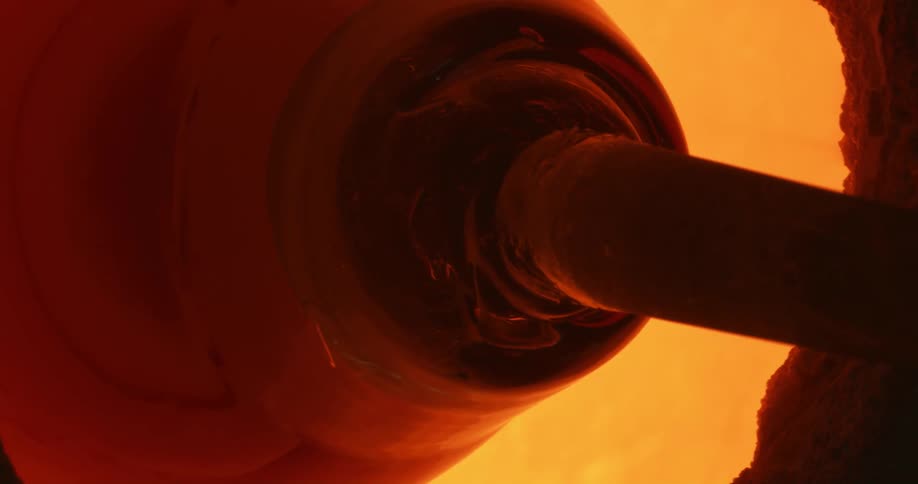 Glass on the end of a pole spun in a hot glowing kiln furnace