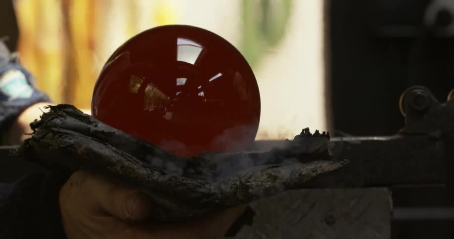 A person molding a ball glass with a cloth as the cloth brings smokes