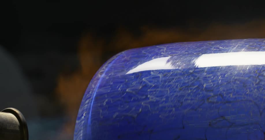 A blue vase with dark design is being touched with flames