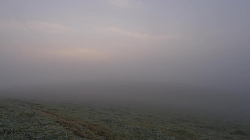 Heavy fog and clouds are above the field below