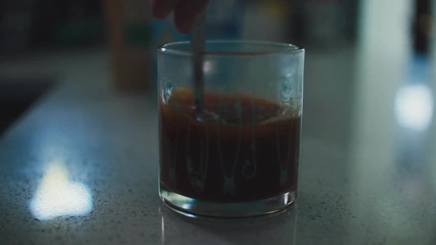 A person pouring a cup of coffee and stirring it with a spoon