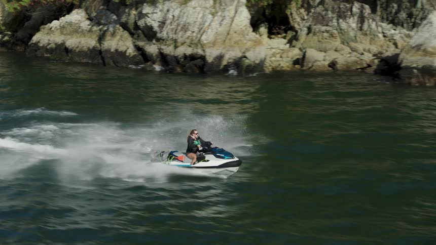 Aerial view of a woman riding a jet ski on a lake in the mountains
