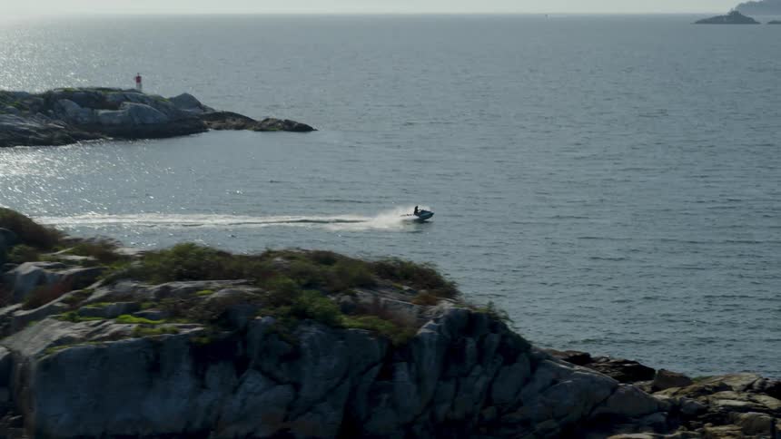 Someone in a moving speedboat on the sea at midday