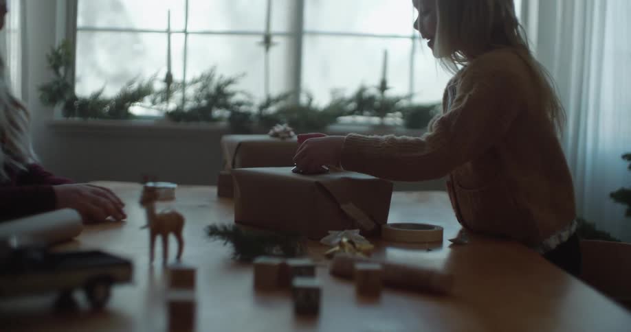 A mother and daughter wrap gifts together