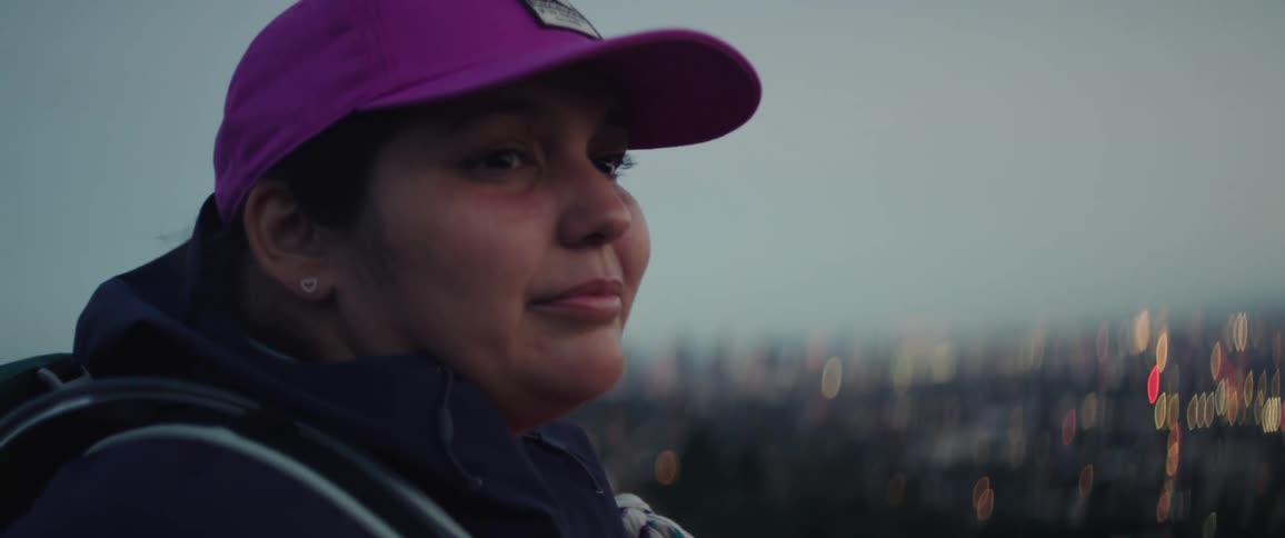 Woman wearing a pink baseball cap looks at the city at evening