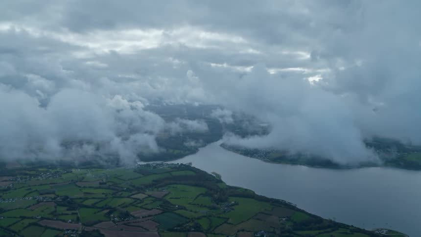 Aerial view of fluffy clouds drifting over the countryside and meandering river