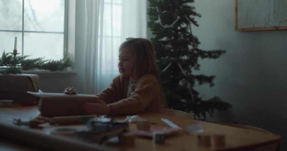 Mother and daughter sitting at table wrap christmas gifts laughing