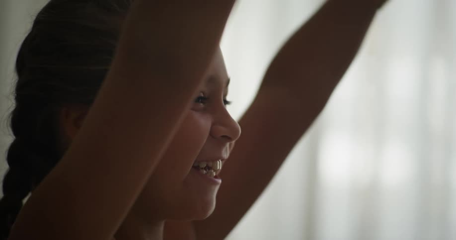 A child celebrates while watching something on TV